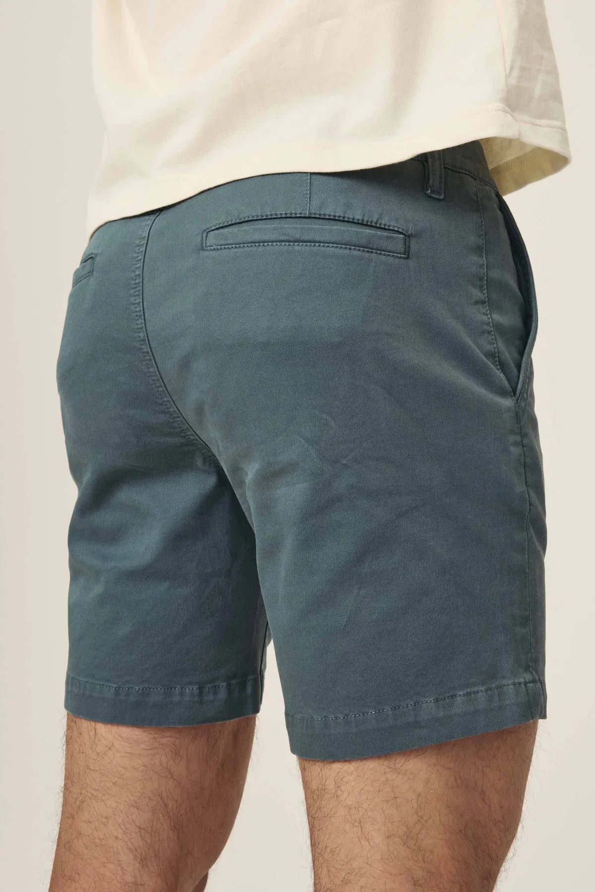 Rear view of dark teal chino shorts with welt pockets and a white t-shirt.
