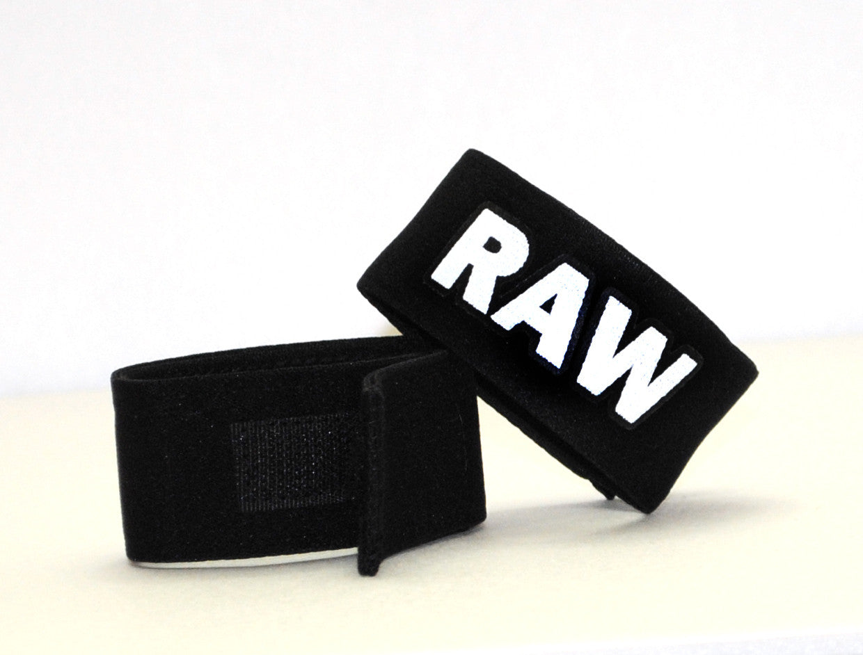 Two black, adjustable velcro cock rings with the word "RAW" stitched in bold white lettering.