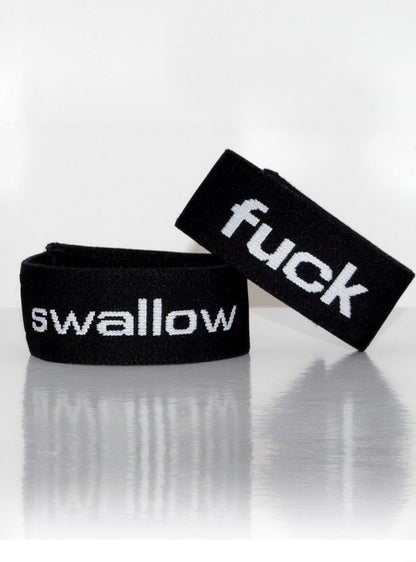 Two black elastic cock rings with white text reading "swallow" and "fuck" against a white background.