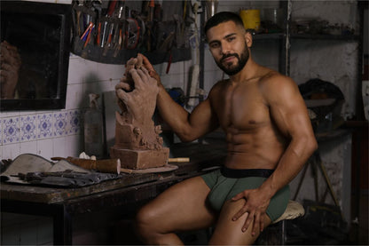 A clay sculpture of a hand being shaped by the artist wearing xtremen 91252 microfiber mesh trunks in military green