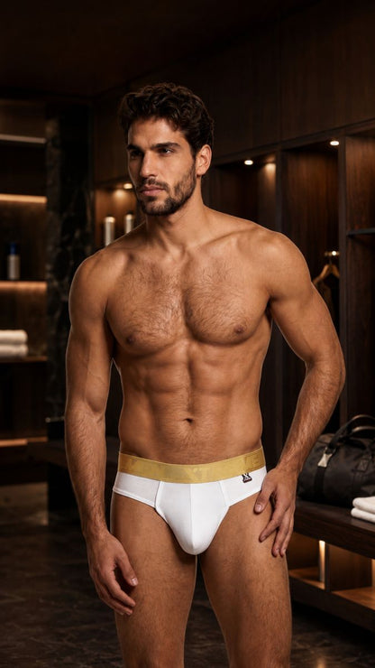 Xtremen white bikini brief with a gold branded waistband on a fit, shirtless man.