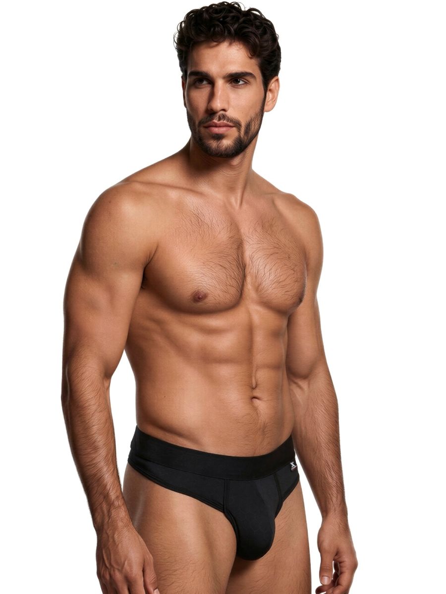 Xtremen black thong on a model, featuring a smooth, matte fabric and a thick branded waistband.