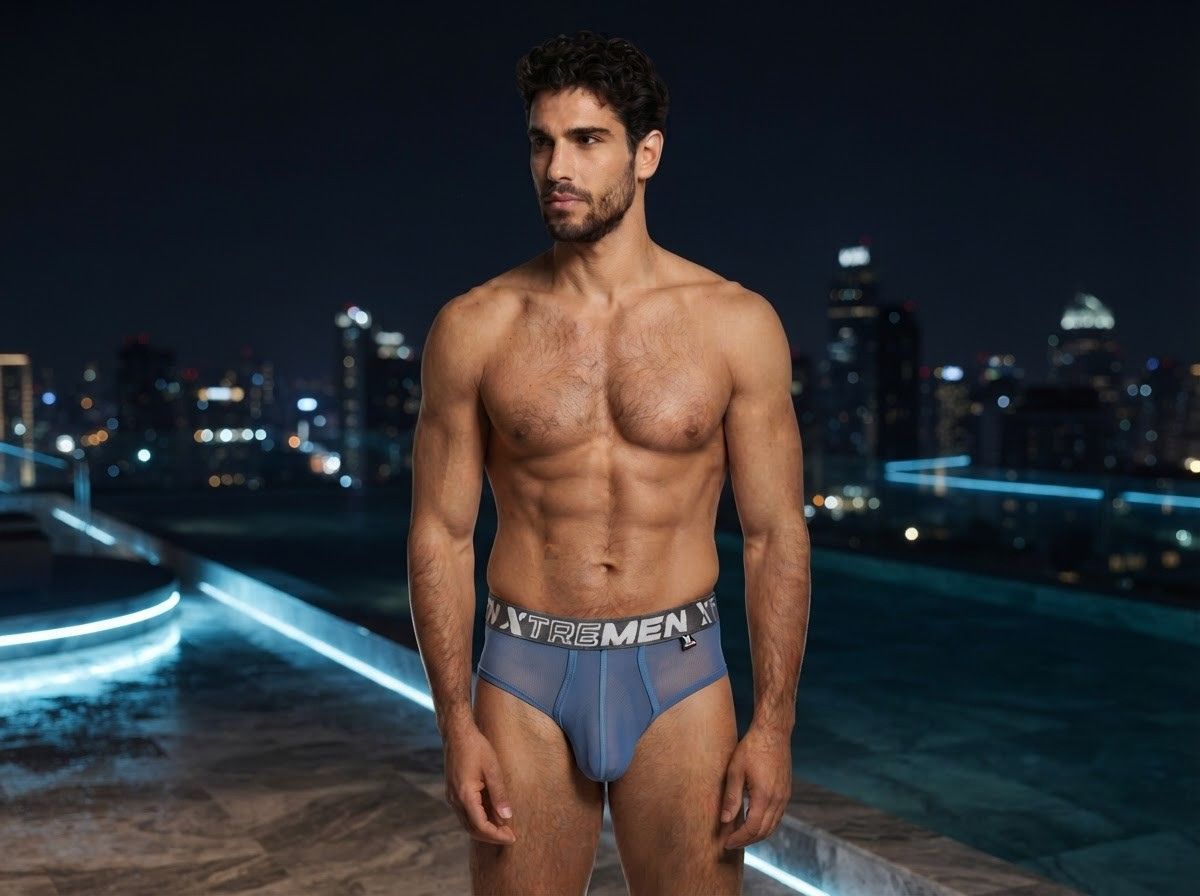 Xtremen blue bikini brief in sheer mesh fabric with a branded elastic waistband on a model at night.