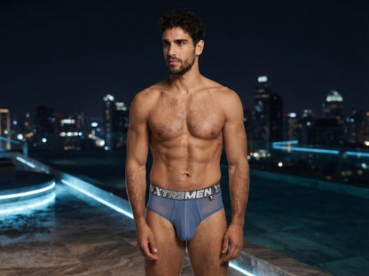 Xtremen blue bikini brief in sheer mesh fabric with a branded elastic waistband on a model at night.