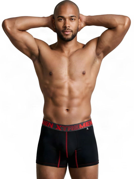 A man poses in black boxer briefs with red stitching and logo waistband.