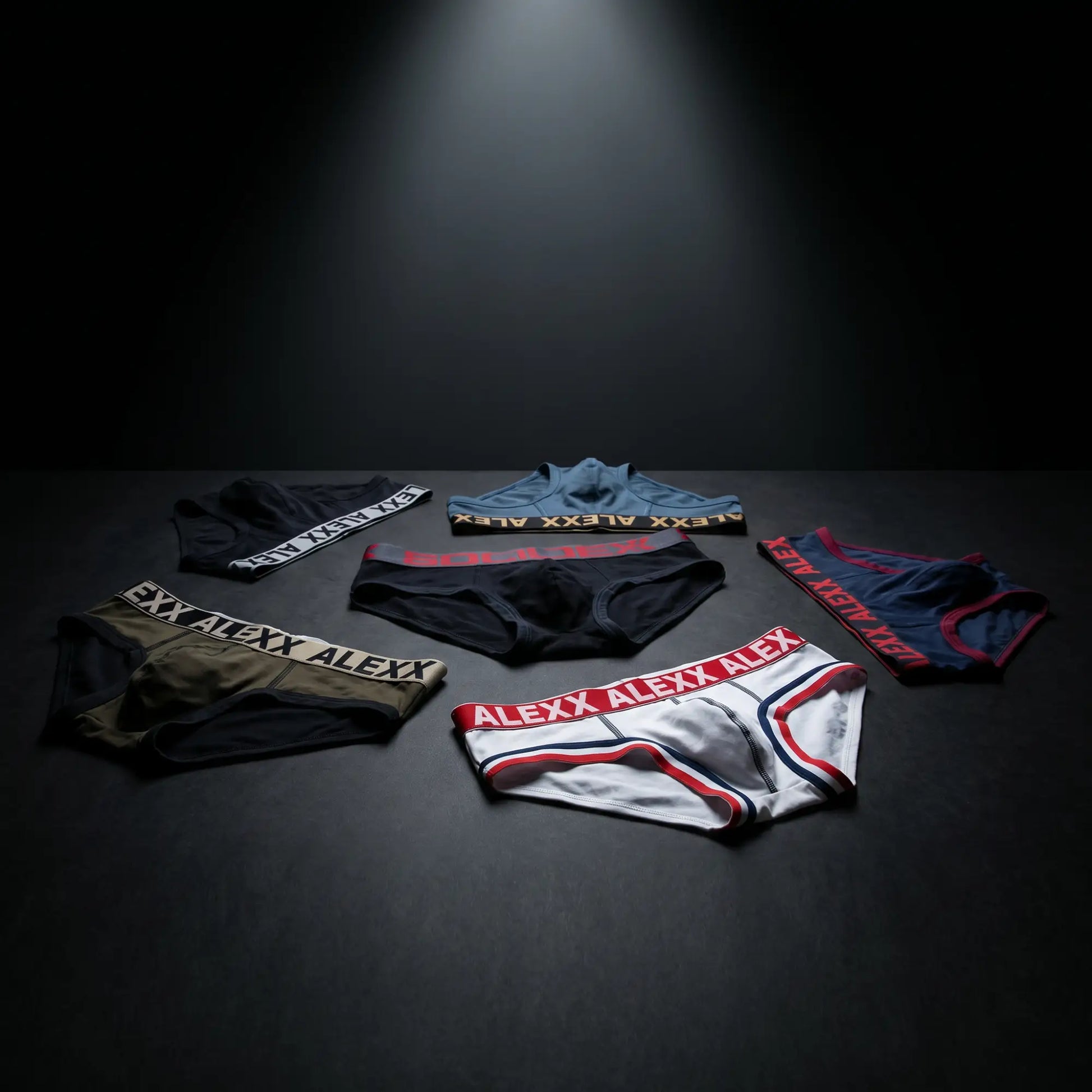 Five pairs of colorful Alexx branded briefs arranged in a semi-circle on a dark surface.