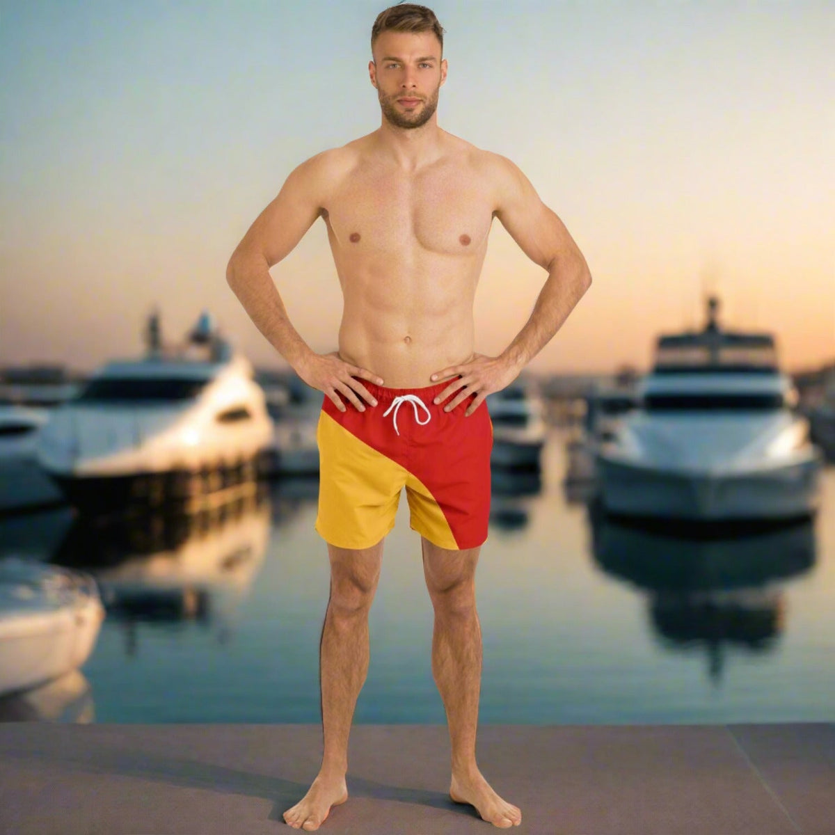 Men's swim shorts by Maris Equi in red and yellow featuring a drawstring waistband shown on a model by boats.