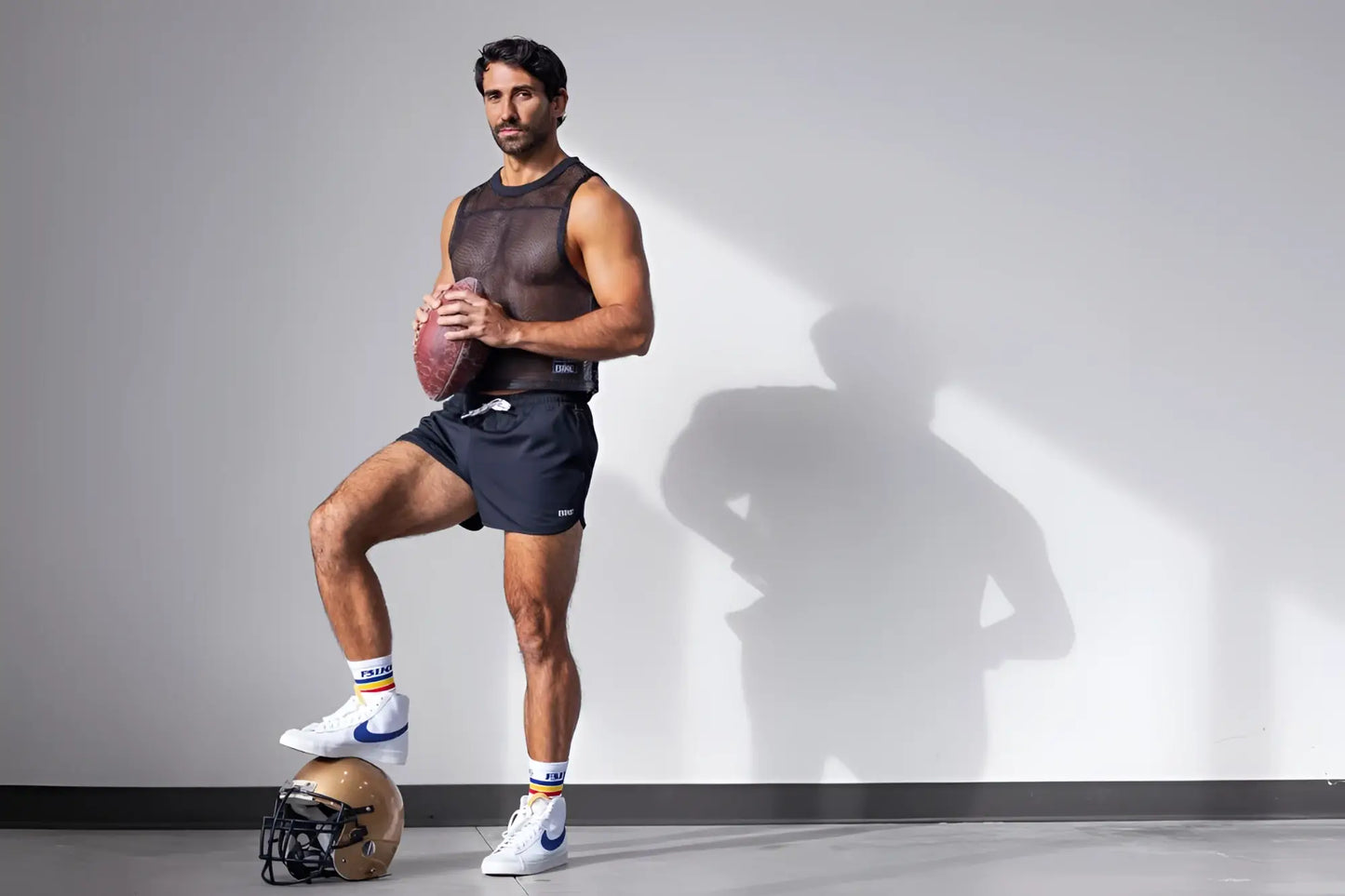 A gold and black football helmet shown alongside black track shorts.