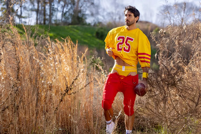 Yellow football jersey with number 25 worn over a yellow Bike Athletic jockstrap and red football pants.