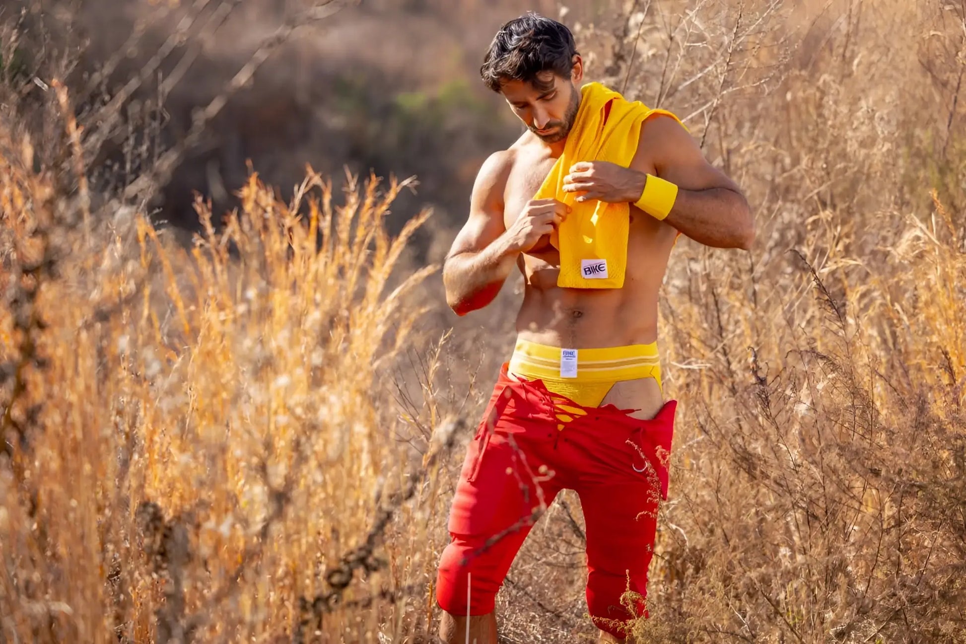 A man outdoors wearing a yellow BIKE Athletic BAS306 original number 10 jockstrap with a small white logo