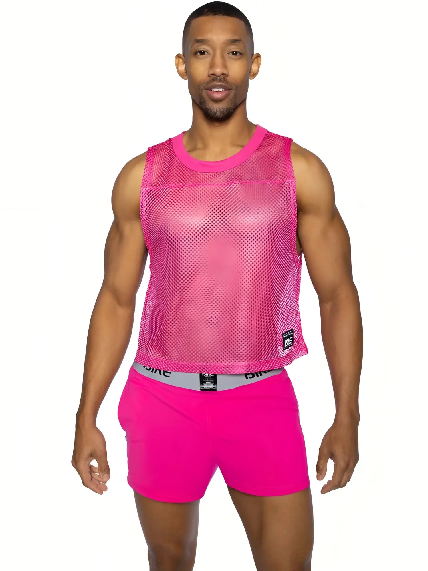 Bright pink mesh sleeveless practice jersey with rounded neckline and small black bike brand tag on lower right side