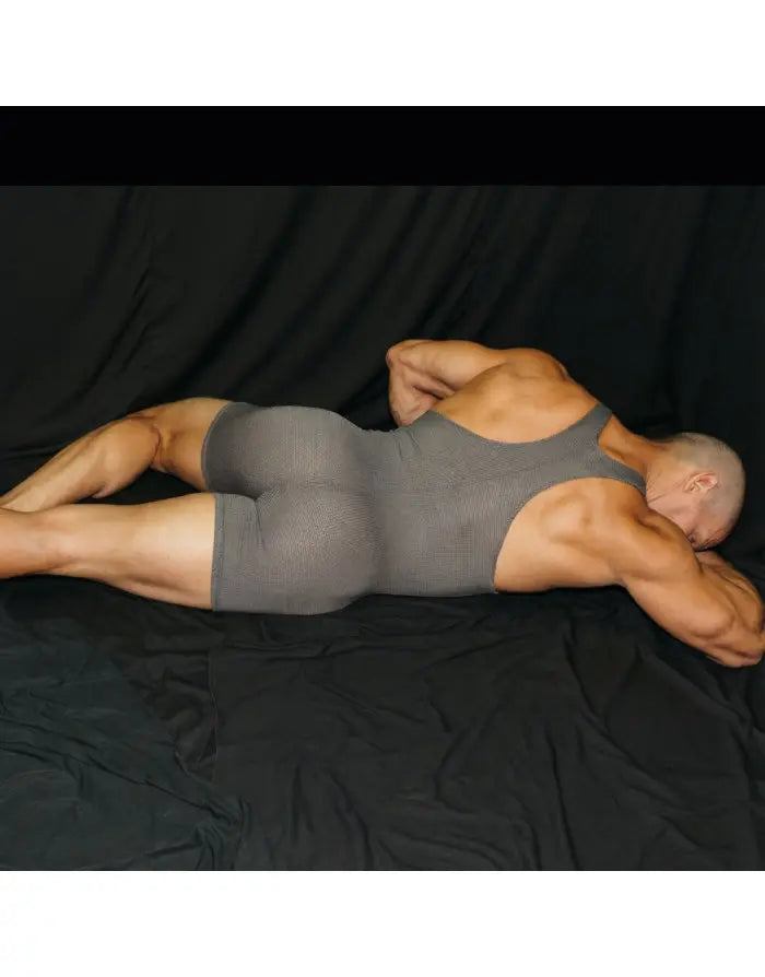 Grey mesh wrestler bodysuit by Arroyman featuring a sleeveless design and form-fitting cut shown on a model lying down.