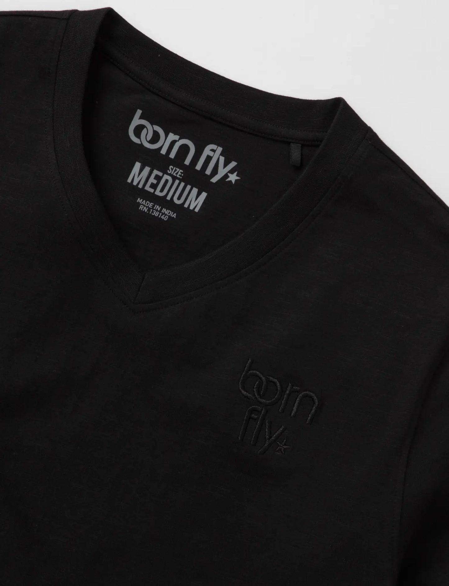Black cotton born fly v-neck tee with subtle logo embroidery on chest and tagline printed inside collar