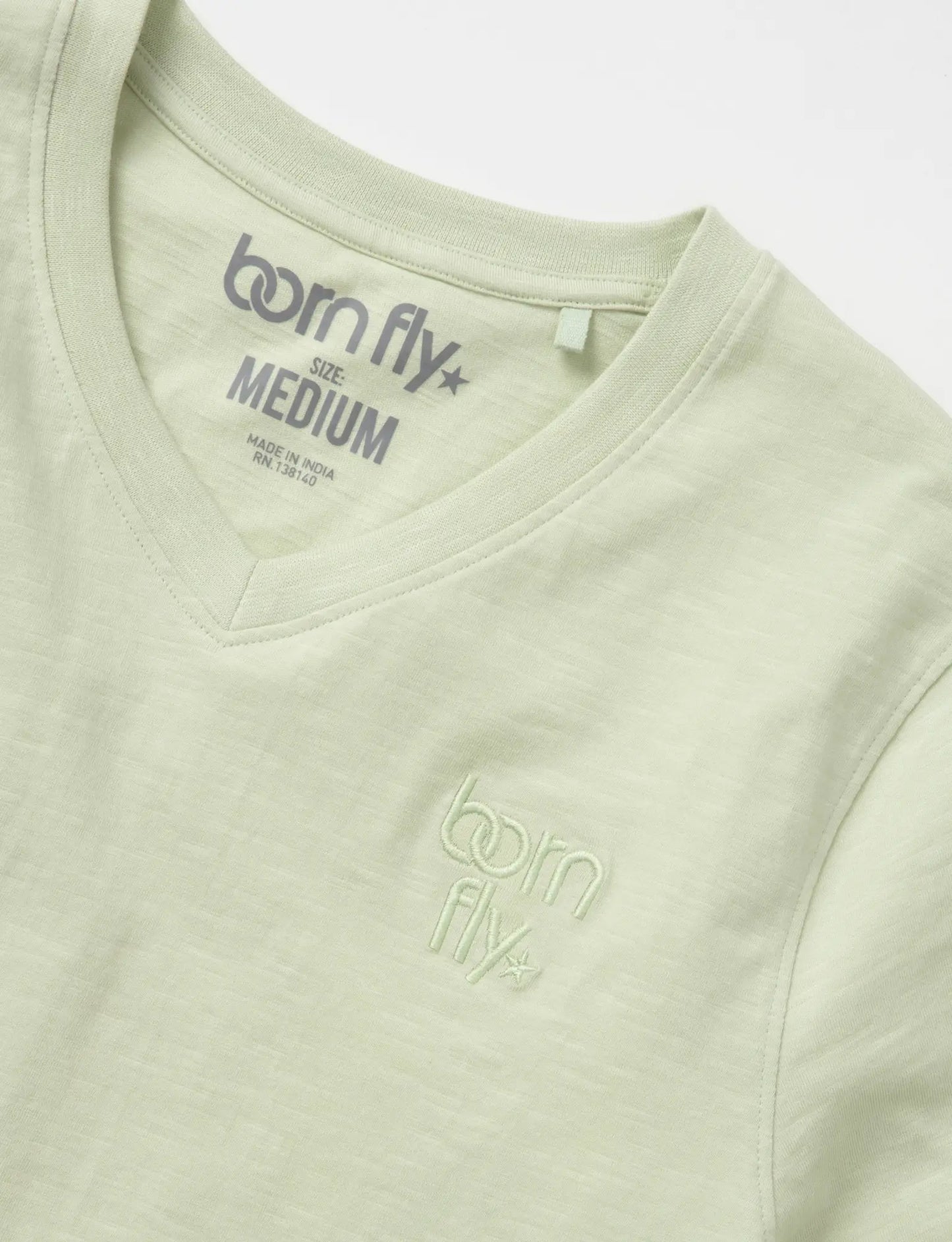 A light green cotton born fly v-neck tee with subtle embroidered logo on the chest and matching inside collar tag