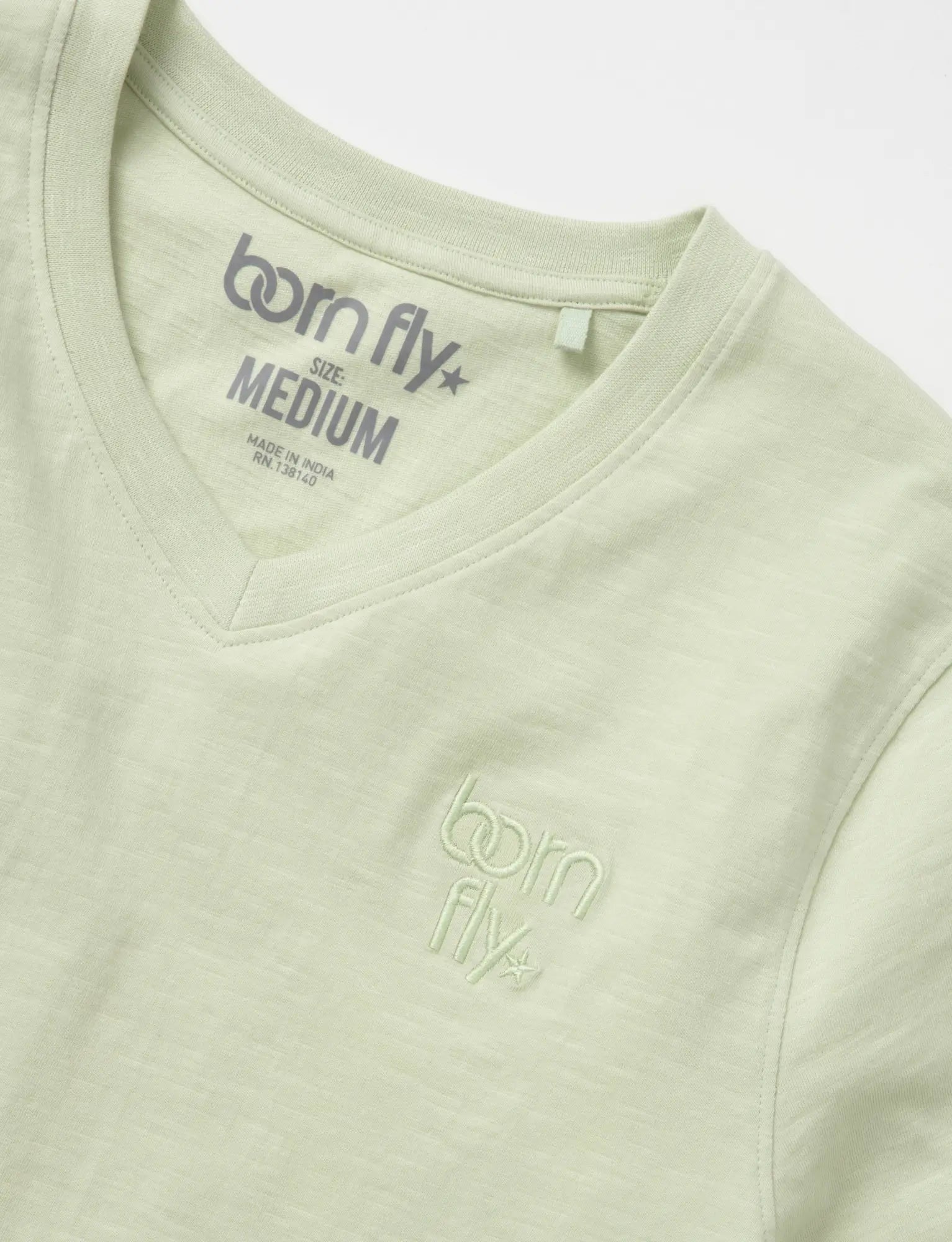 A light green cotton born fly v-neck tee with subtle embroidered logo on the chest and matching inside collar tag