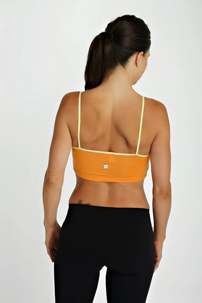 Orange sports bra top tangerine with thin yellow straps and a small brand logo visible on the back side