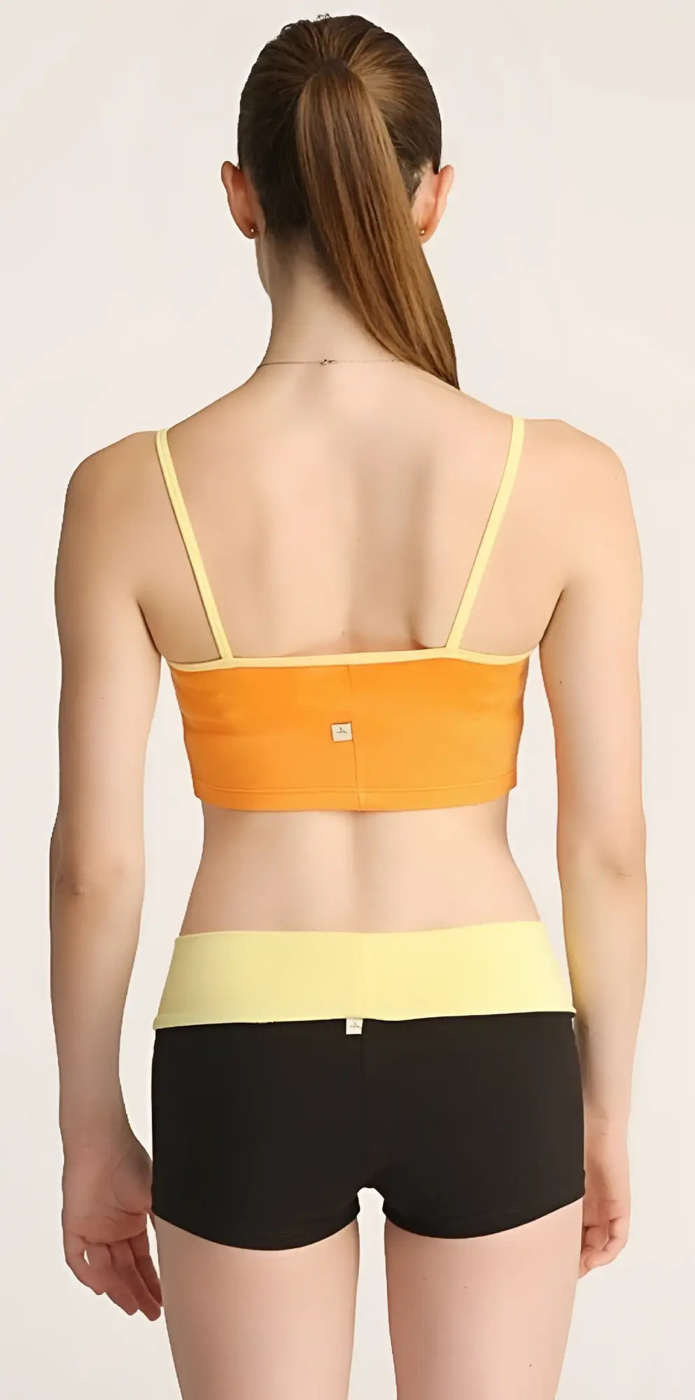 Orange and yellow strap sports bra paired with black bumble short shorts for activewear use