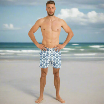 Men's swim shorts in blue and white baroque pattern made by Maris Equi shown on a model at the beach.