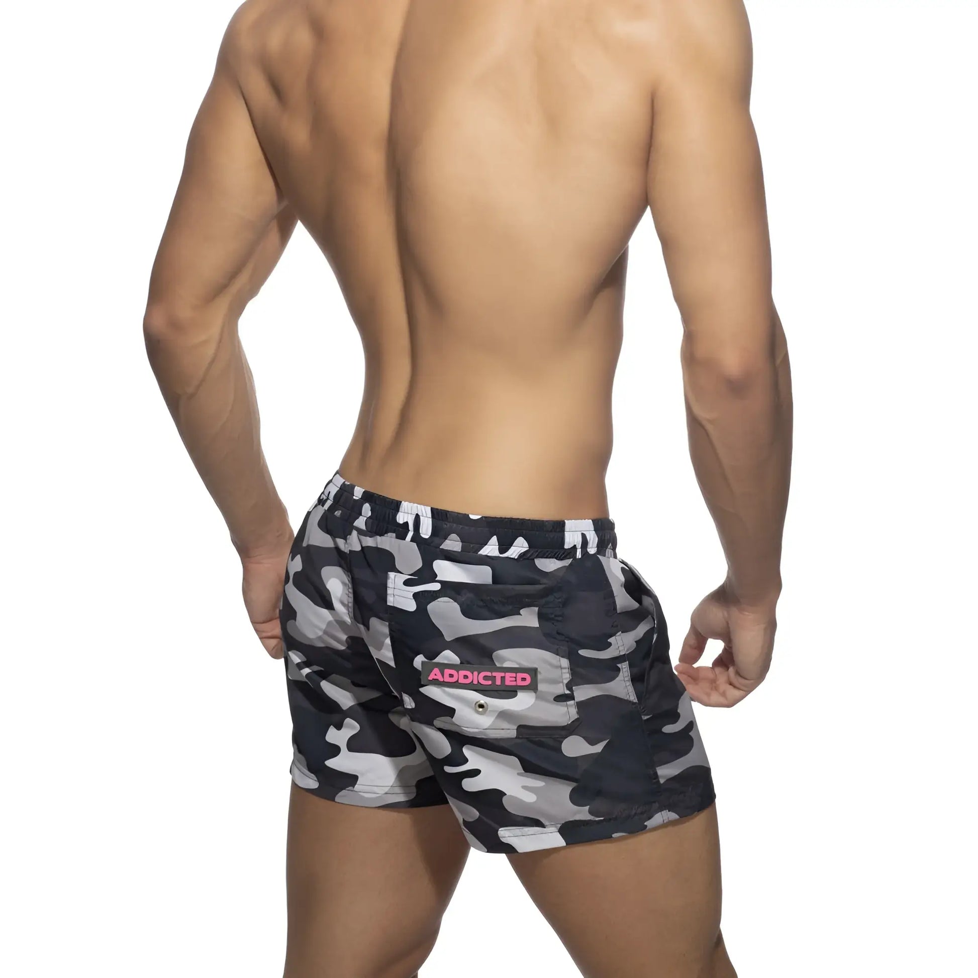 Back side of black and gray camouflage swim shorts with pink addicted logo patch on the back pocket