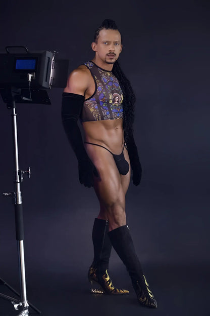 A man wearing a candyMan 99805 stained glass tank top in black with gold patterns and matching thigh-high boots