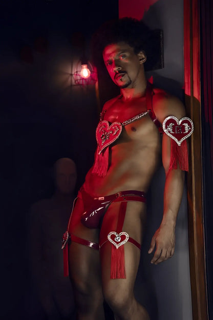Red heart-shaped rhinestone embellishments with tassels adorn a shiny red latex candyman 99819 dom thong in gloss wine