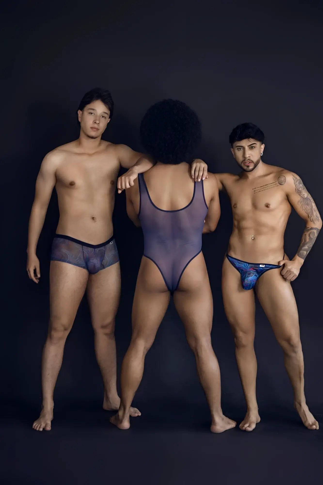 The central figure wears a sheer dark purple one-piece bodysuit with black trim in CandyMan 99873 multicolor print trunks