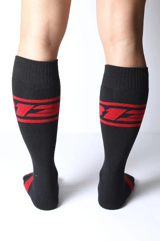 Black knee-high socks with red logo detail worn by a model by CellBlock 13