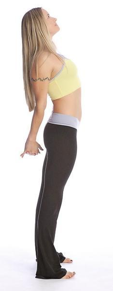 A woman wearing 4-rth women’s classic black yoga pants with white side stripes and a yellow sports bra with gray trim