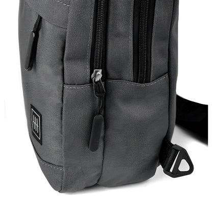 Dark gray canvas crossbody sling bag with black zippers and small square logo patch for everyday use