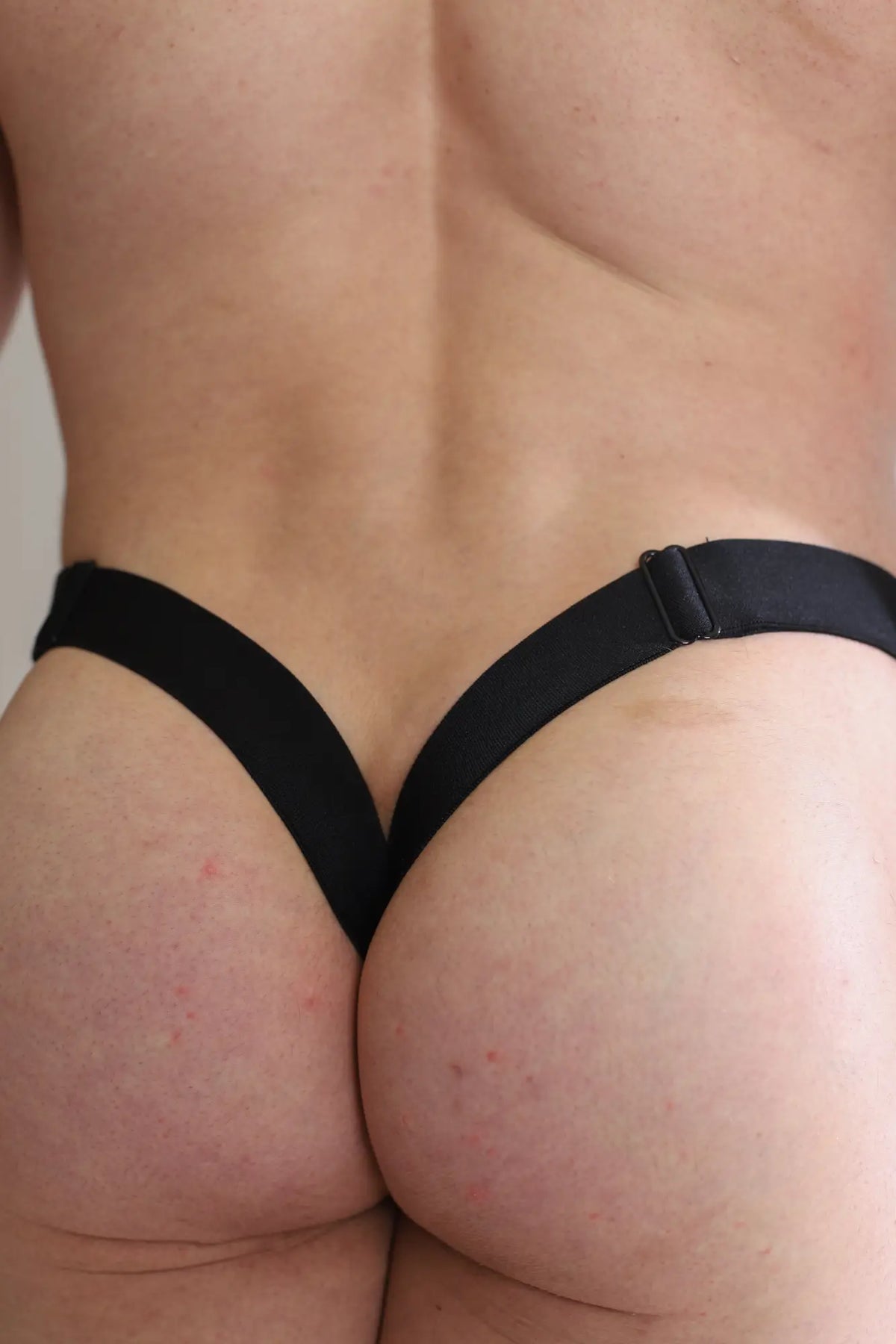 Deep back v jockstrap black thong with sleek minimalist design and adjustable elastic straps shown from the back