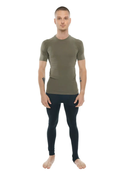 A man wearing a fitted olive green designer raglan crew-neck compression shirt with black leggings