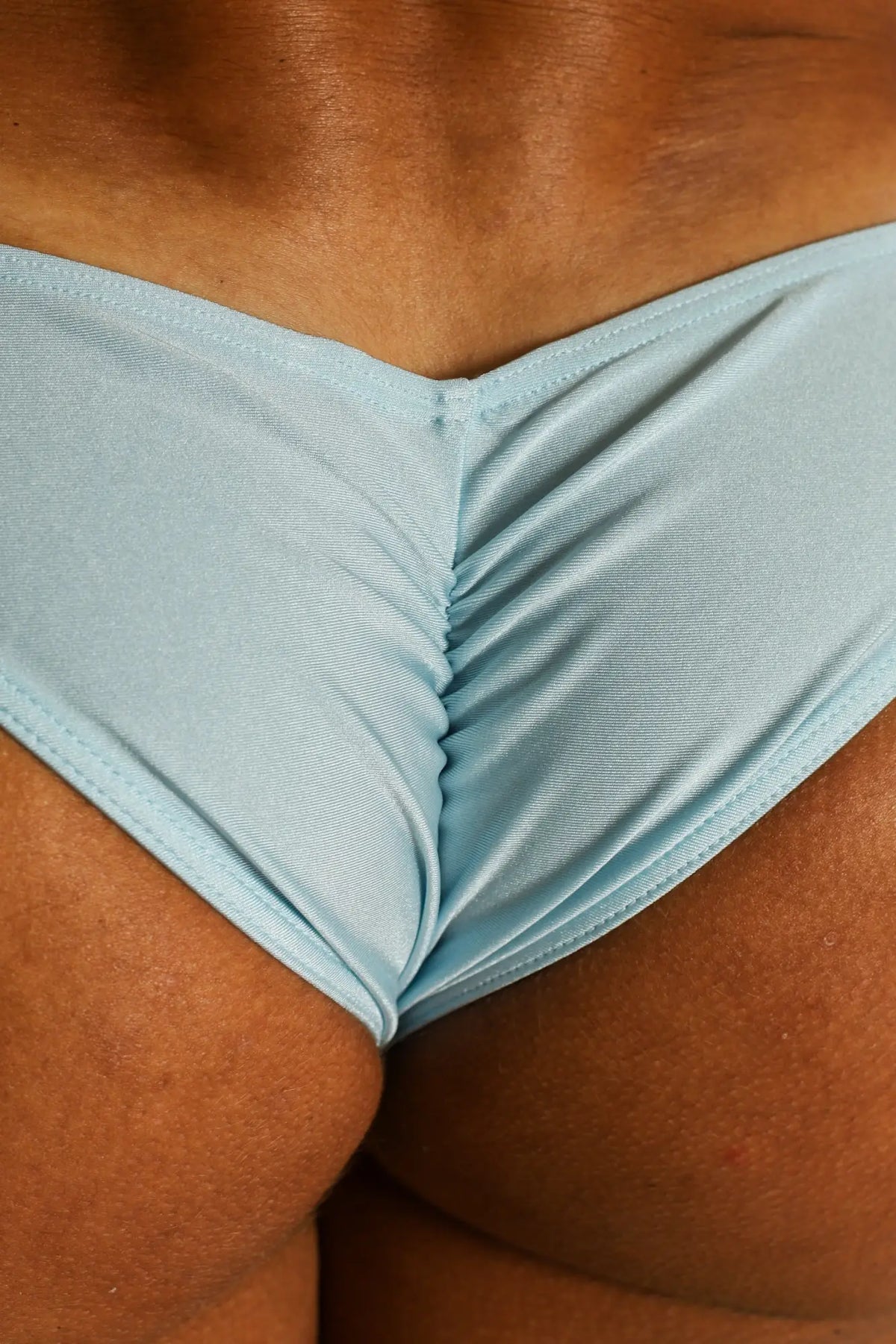 Light blue dynamic scrunch-butt bikini briefs with v-shaped front and subtle ribbed texture in a form-fitting style