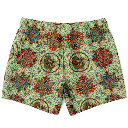 Green swim shorts with a colorful mosaic pattern featuring floral and geometric designs by Maris Equi.