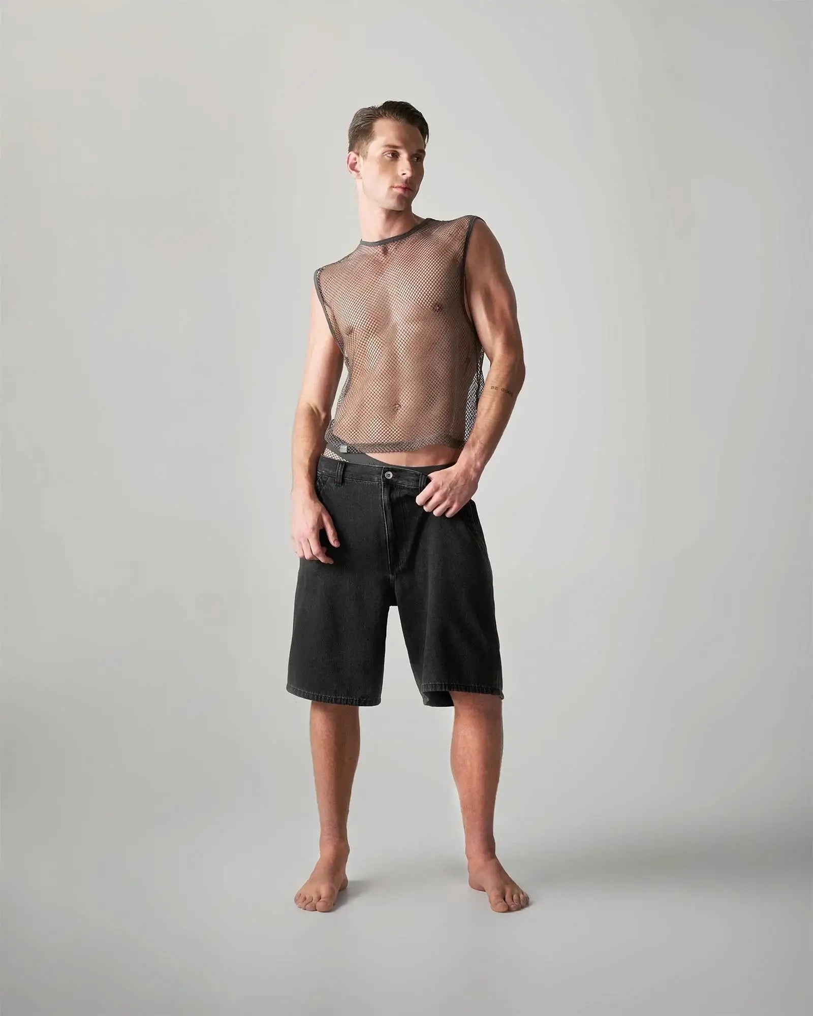 Black denim shorts with straight-leg cut and button closure paired with edge net mesh muscle tank