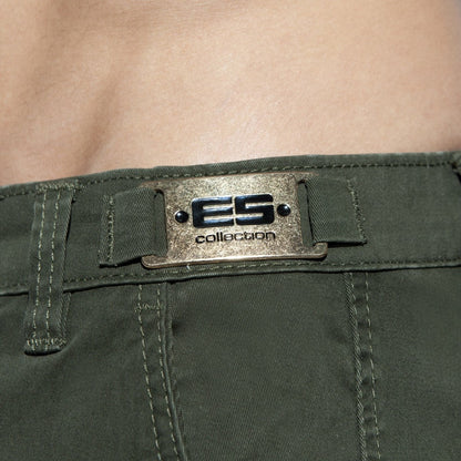Close-up of olive green cargo shorts featuring a metallic ES Collection brand plate on the waistband.
