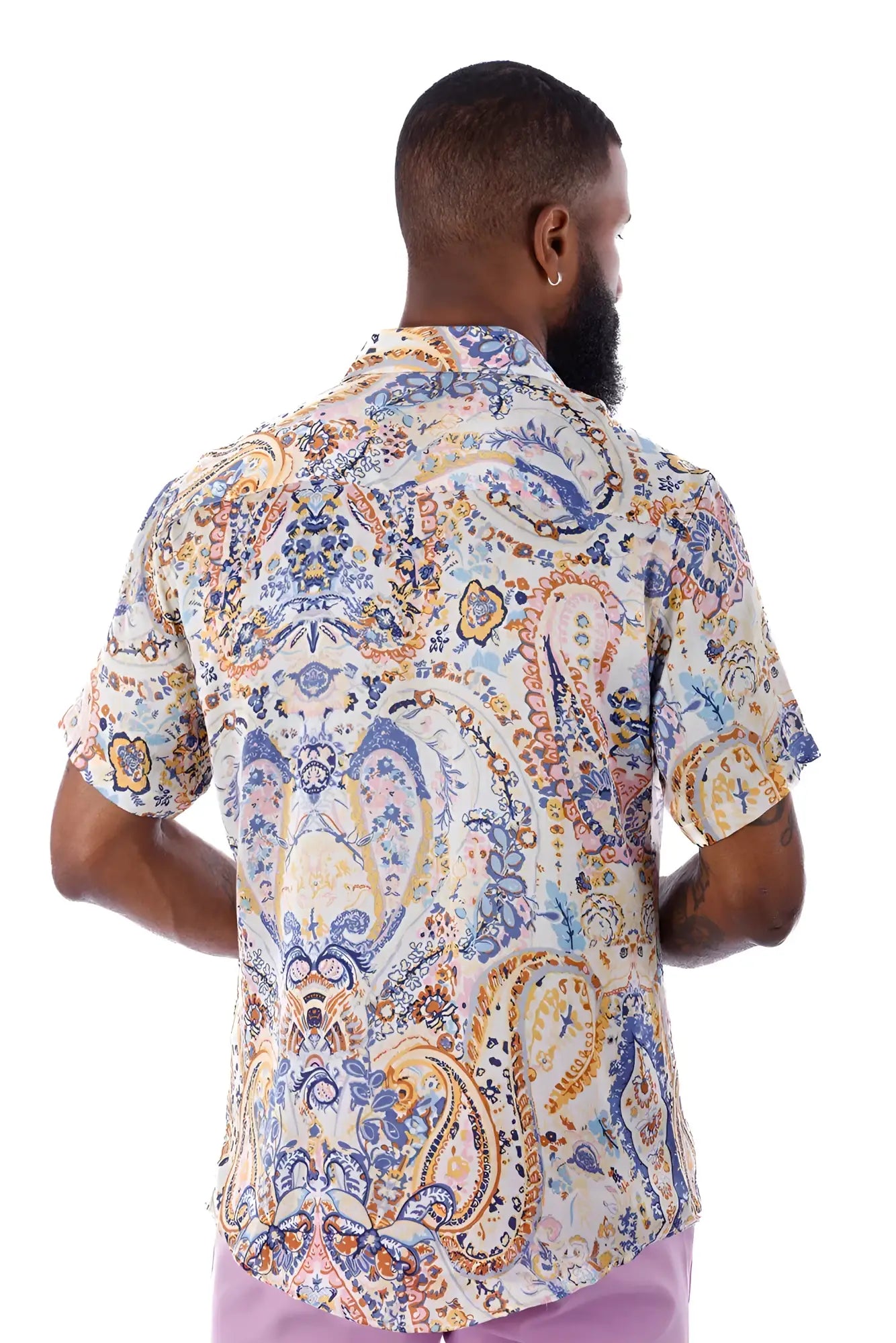 A man wearing an exclusive buzz s/s shirt with a blue gold and cream paisley pattern on a light background