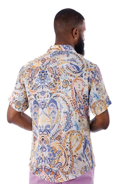 A man wearing an exclusive buzz s/s shirt with a blue gold and cream paisley pattern on a light background