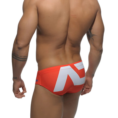 Vibrant orange extra-large logo brief swim trunks with bold white geometric logo on the back side