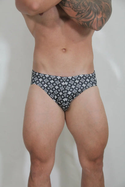 Black swim brief with a repeating white geometric pattern called fancy symbols swim brief