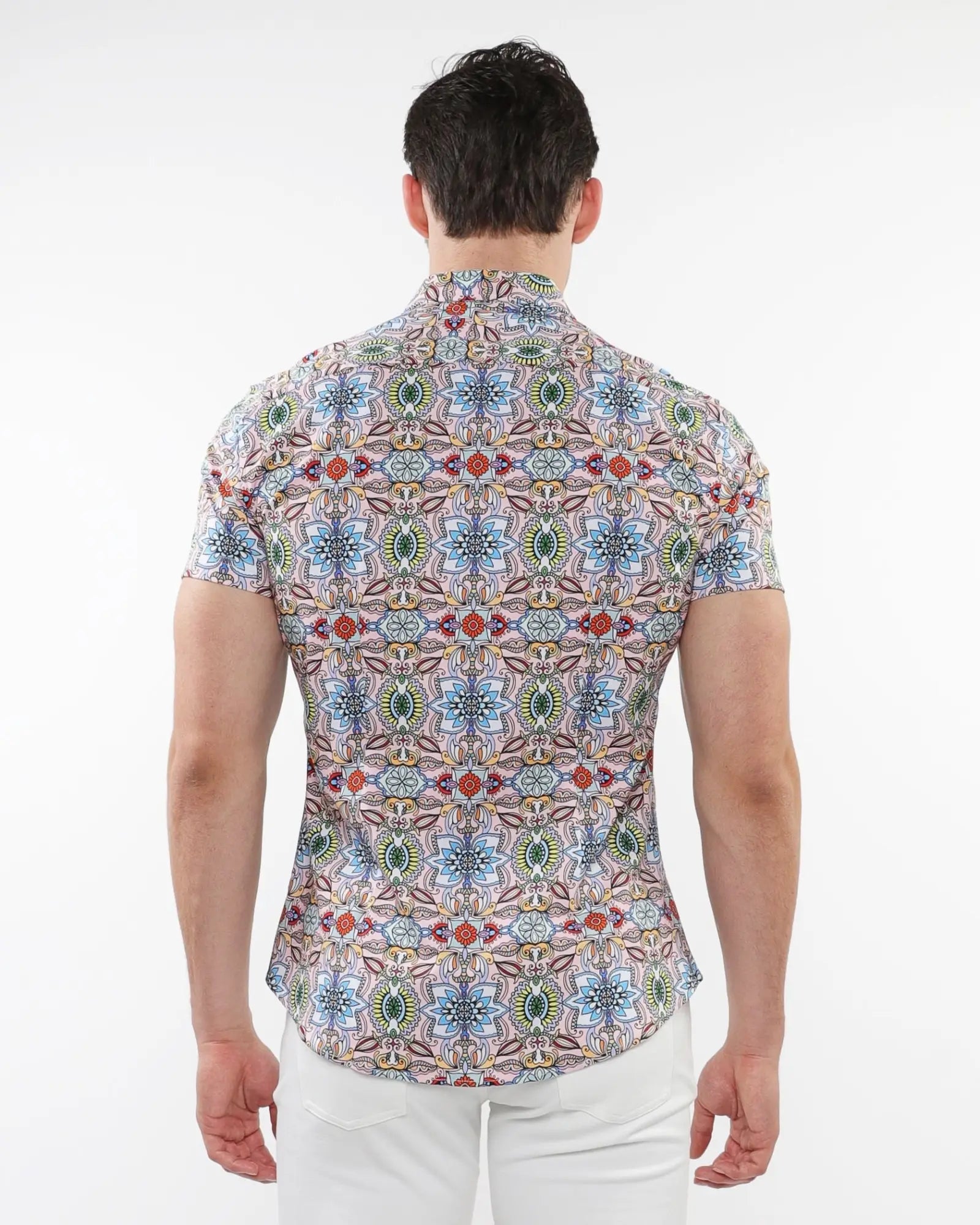 A man wearing a fauna print stretch knit short-sleeved shirt with colorful geometric and floral patterns on light fabric