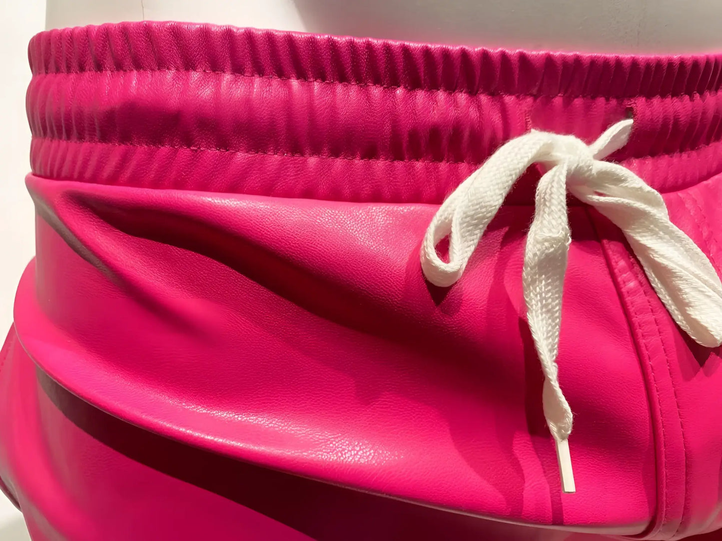 Bright pink faux leather shorts with white drawstring waistband in a style called faux leather short