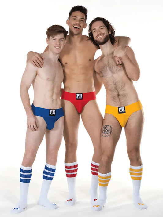 Three men wearing brightly colored low-rise briefs with black fk logo and white tube socks with matching stripes
