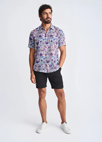 A man wearing a floral lightweight linen tencel short-sleeved shirt in shades of purple blue and pink