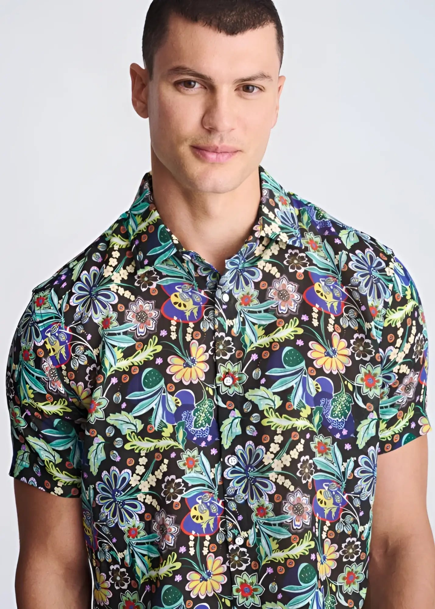 A vibrant floral lightweight linen tencel short-sleeved shirt with green blue yellow and purple pattern on dark background