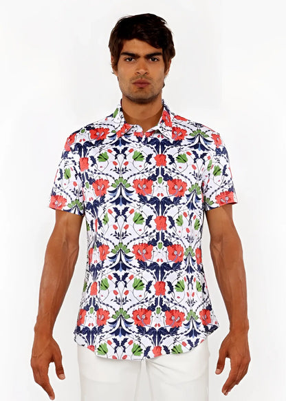A man wearing a white floral print stretch knit shirt with red poppies green leaves and navy blue vines