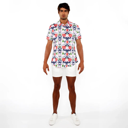 A man wearing a floral print stretch knit shirt with red blue and green flowers on white short-sleeved button-up shirt