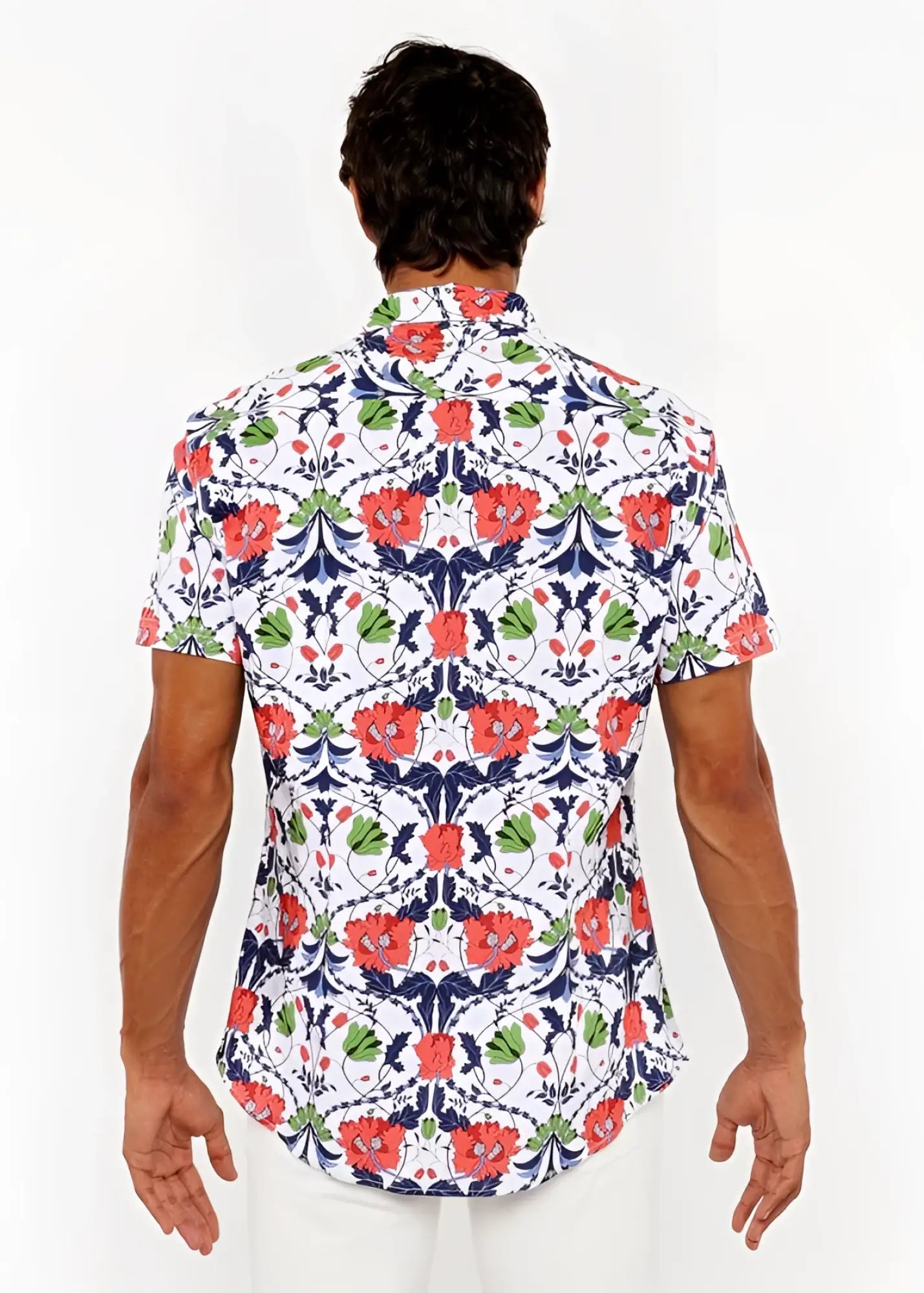 A man wearing a white floral print stretch knit shirt with red poppies and green leaves on navy blue vines