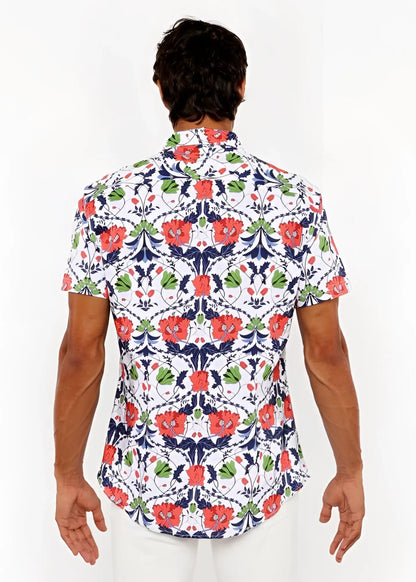 A man wearing a white floral print stretch knit shirt with red poppies and green leaves on navy blue vines