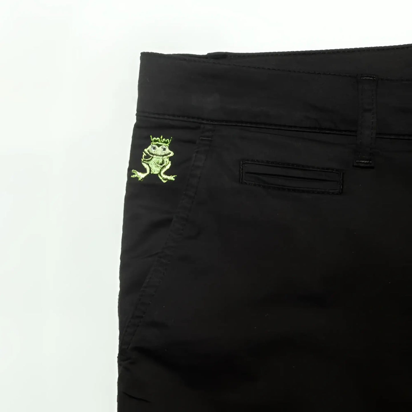 Back side of black denim frog chino short featuring an embroidered green frog with crown on the pocket
