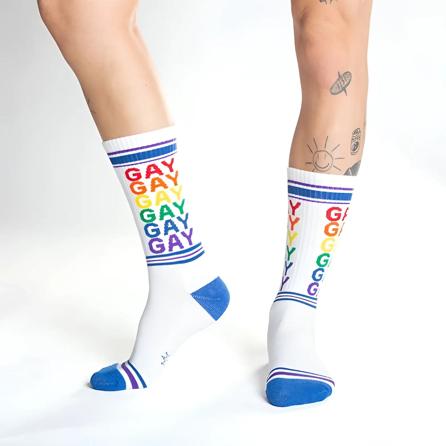 White crew socks with rainbow colored gay text and blue toe heel and cuff accents for pride wear